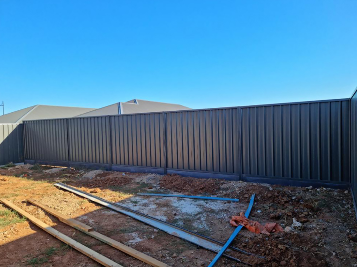 Long dark steel fence along a new home's cleared backyard