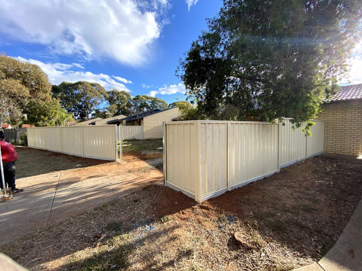 Cream steel fence enclosing a corner front yard beside a footpath