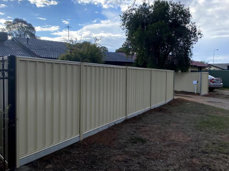 Cream steel fence along a front lawn next to a black gate
