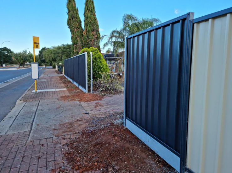 Dark steel fence with plinths meeting an older cream fence by a footpath