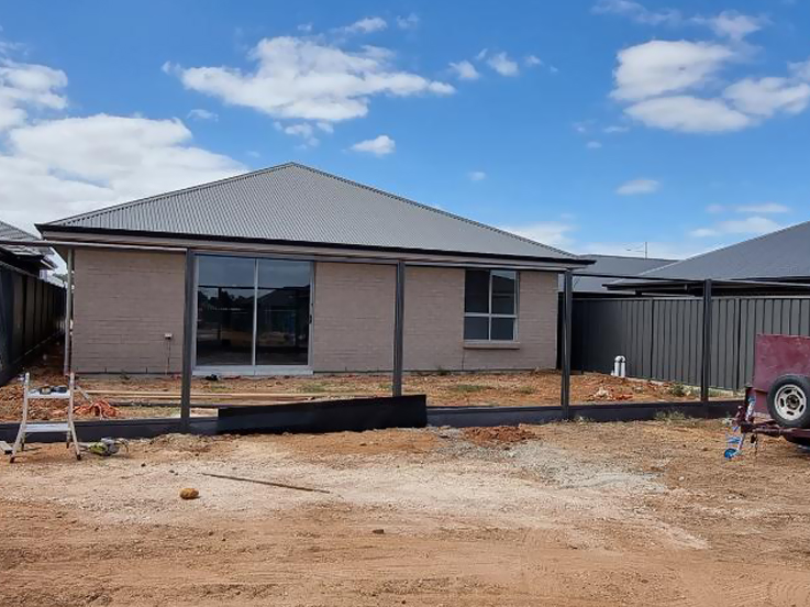 Black steel fence posts and plinths in front of a new home's bare yard