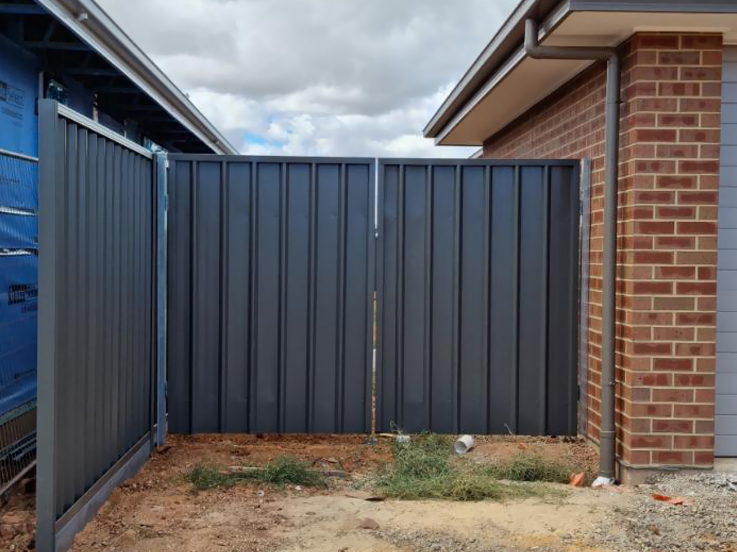 Dark steel fence panels enclosing a corner beside a brick home