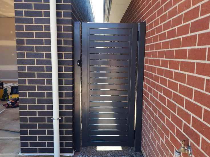 Dark slatted side gate between two brick walls