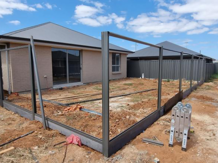 Steel fence frames with top rails around a new home's backyard