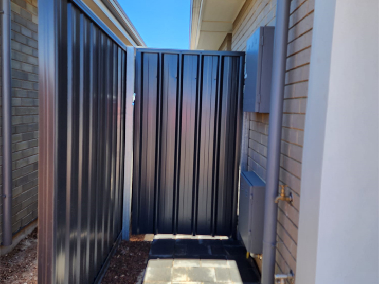 Dark steel side gate and fence in a narrow side passage