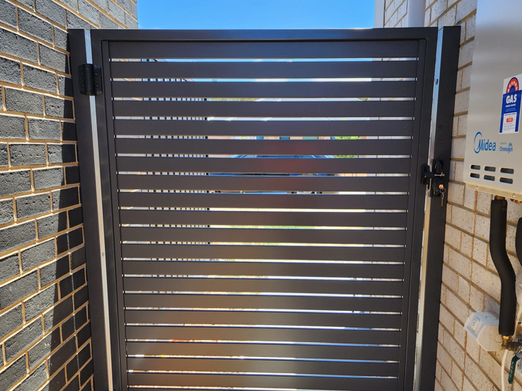 Grey slatted side gate beside a wall-mounted hot water unit