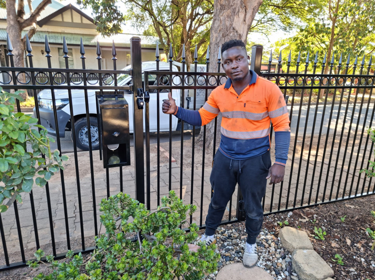 Worker in hi-vis giving a thumbs up beside a black tubular fence