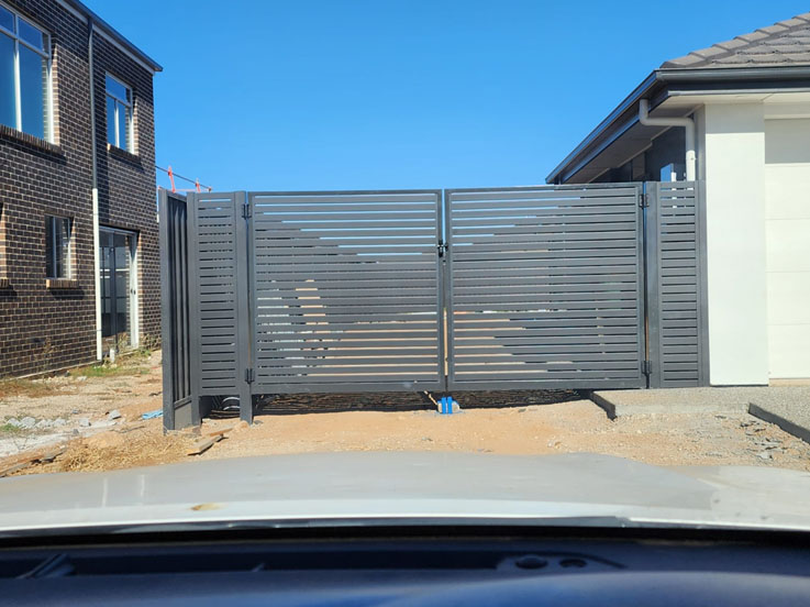 Grey slatted double driveway gates between two new homes