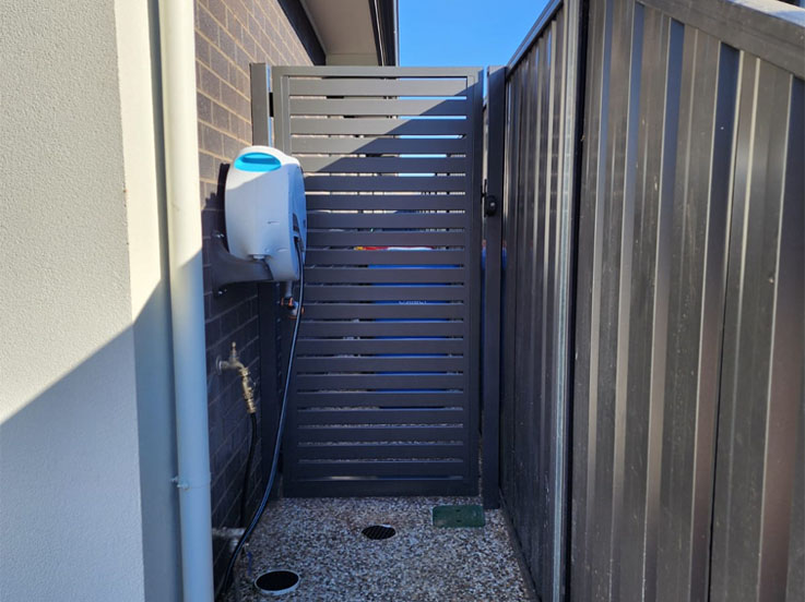 Grey slatted side gate beside a dark steel fence