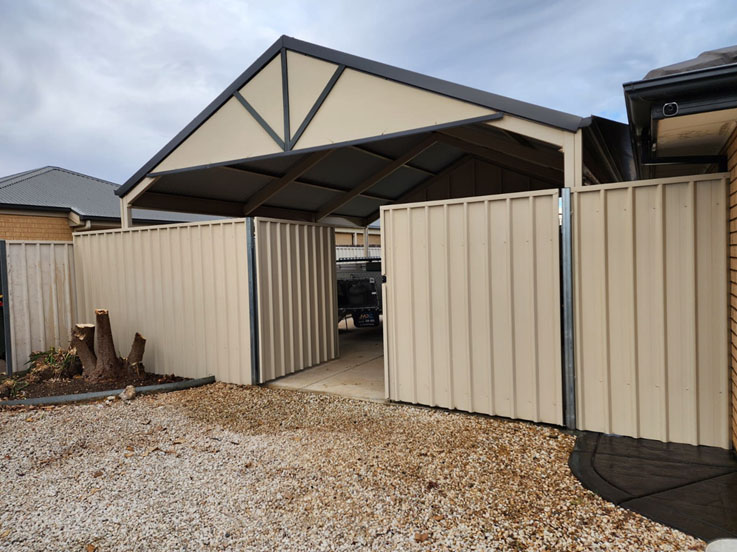 Cream steel fence with one gate open in front of a carport